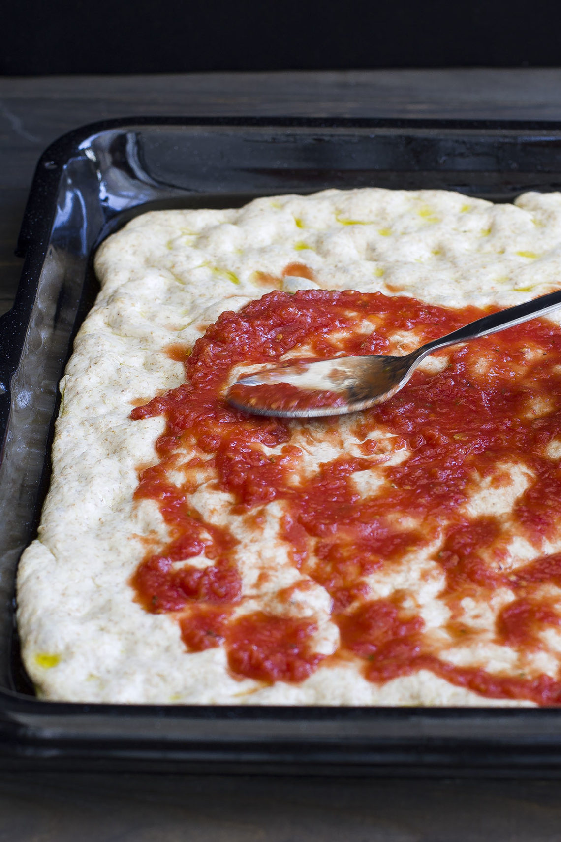 Step 4: Ungete con l'olio una teglia di forno prima di stendervi all'interno l'impasto per la pizza e conditelo con la salsa di pomodoro, l'olio del Cilento, il basilico, l'aglio e la vendita prima di infornare la pizza in forno preriscaldato a 200 °.